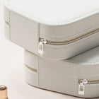 Two stacked light grey vegan leather travel jewelry organizers with zipper closures.