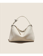 Elegant cream-colored pebbled leather handbag with a curved handle and zipper closure.