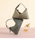 Two modern grey pebble-grain leather handbags and a gold-capped perfume bottle on a pink surface.