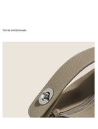 Close-up of a textured taupe leather handbag strap with a silver metallic fastener.
