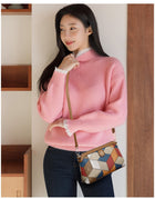 Woman wearing a pink knit turtleneck sweater and a patterned crossbody bag.