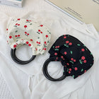 Two fabric drawstring pouches with cherry patterns, one cream and one black, on white fabric.