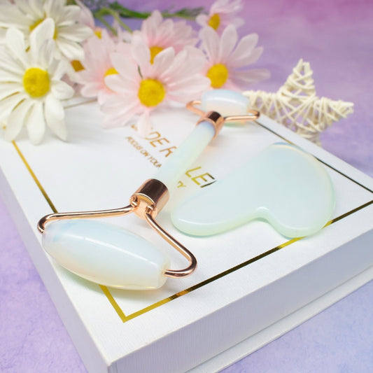 White quartz face roller and gua sha set on a white box with white flowers.