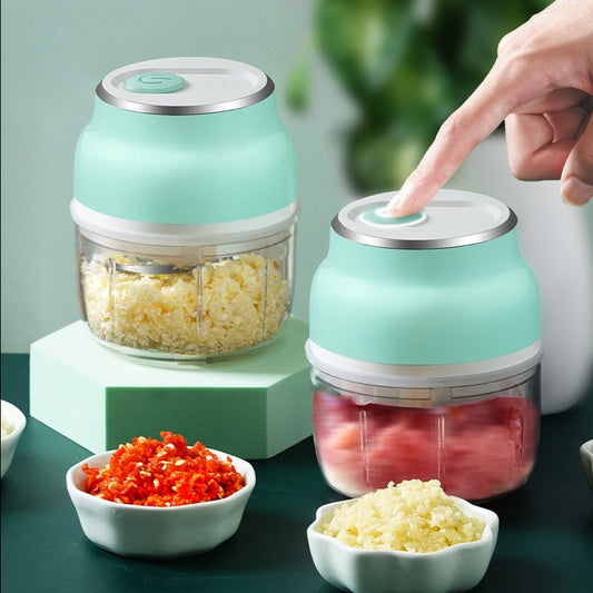 Two mint green electric mini food choppers with chopped garlic and chili in small bowls.