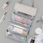 Gray hanging toiletry bag with mesh compartments filled with skincare and makeup products.