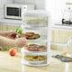 Multi-tier white plastic food storage container with various foods in a kitchen setting