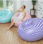 Woman relaxing in a pink swirl pattern inflatable bean bag chair among teal and purple ones