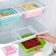 Stackable clear plastic food storage containers with colorful lids in a refrigerator.