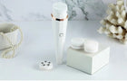 White electric facial cleansing brush with multiple interchangeable brush heads and massage rollers.