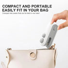 Hand holding a compact white mini bag sealer near a cream-colored handbag.