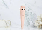 Pink electric facial cleansing brush with soft bristles on a marble background.