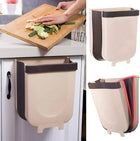 Collapsible hanging kitchen trash bin attached to a cabinet door for food waste management.