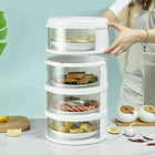 Three-tier white electric food steamer with seafood and vegetables on a kitchen counter