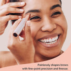 Smiling woman using a rose gold precision eyebrow trimmer for painless brow shaping.
