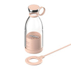 Portable pink electric juice blender bottle with wireless charging base.