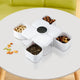 White divided snack organizer tray with assorted nuts and seeds on a white table.