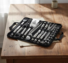 Stainless steel BBQ grill tool set in a black carrying case on a wooden table